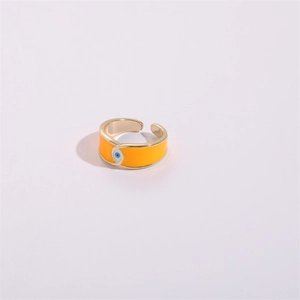 Detail shot of orange enamel 14K gold open ring with evil eye pattern on a light background