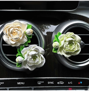 Detailed close-up of white and cream jasmine diffuser flowers on car air vent