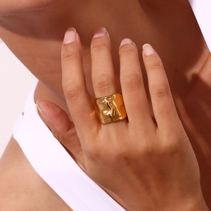 Anello a fascia larga in acciaio inossidabile placcato oro 18K con trama ondulata sul dito di una modella