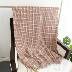Close-up of brown plaid scarf with fringe detail draped over a wooden armchair