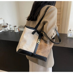 Detail view of large beige and brown canvas tote bag with black leather shoulder straps