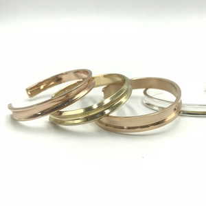 Three minimalist C-shaped concave stainless steel cuff bracelets in gold, silver, and rose gold