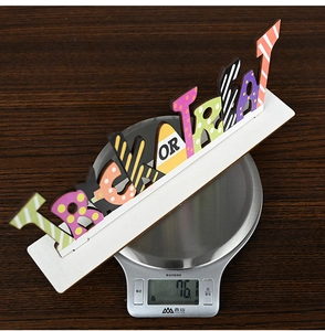 Detailed view of Halloween Trick or Treat wooden letter sign on a digital weight scale