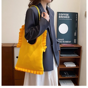 Detail of bright yellow ruffled knit tote bag featuring large pleated decorative edges