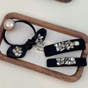 French vintage black bow hair tie and rhinestone hair clip set on a wooden tray