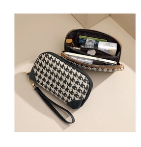 Detail of houndstooth wristlet bag showing three-layer interior capacity and metal zipper