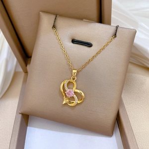 Close-up of golden heart necklace with pink gemstone and small zircons on velvet