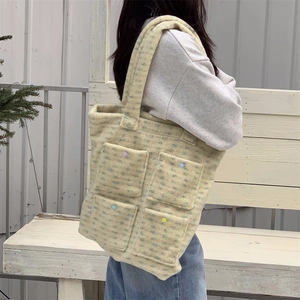 Detail of plush tote bag with four colorful buttoned pockets on a textured beige fabric