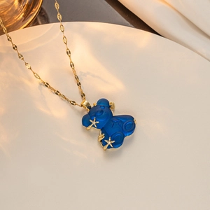Detailed close-up of a gold necklace with a blue transparent bear and star pendant