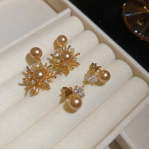Dettaglio orecchini a fiore e fiocco in oro con perle e zirconi brillanti su velluto