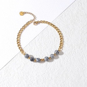 Detail of 18K gold-plated beaded bracelet with black and white textured beads and lobster clasp