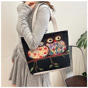 Detail view of ethnic canvas tote bag with vibrant owl embroidery on black fabric