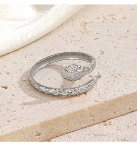 Macro view of silver snake ring with scale texture on beige stone and cream silk