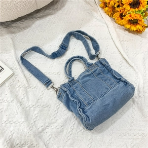 Top view of small blue denim handbag with textures, straps and sunflower decor