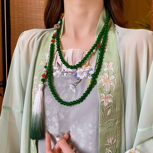 Detail of beaded necklace with green jade beads, tassels and cloisonne floral pendant
