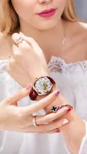 Primo piano di un elegante orologio scheletrato in oro rosa con diamanti al polso