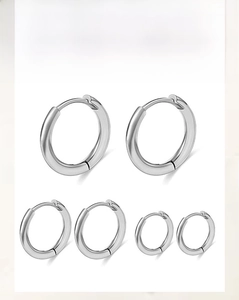 Detailed view of three sizes of polished stainless steel hoop earrings on white background