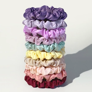 Stack of nine colorful silk satin hair scrunchies in various pastel and deep tones