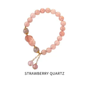 Detail of pink strawberry quartz beads with golden Pixiu charm on a delicate bracelet