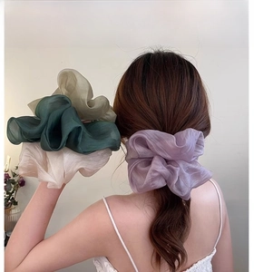 Close-up of oversized mesh scrunchies in pastel purple, green and cream on a low ponytail