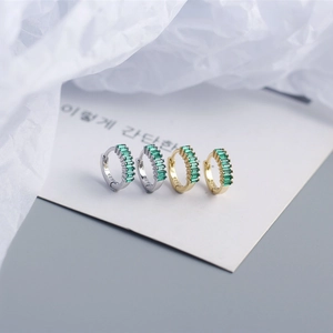 Macro detail of S925 sterling silver hoop earrings set with rectangular green zircons