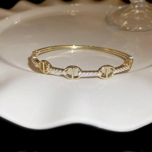 Close-up of gold plated chain link bracelet with sparkling cubic zirconia on white dish