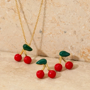Cute gold stainless steel cherry necklace and stud earrings jewelry set on marble