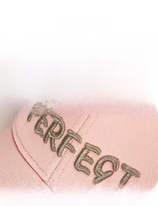 Vue macro de la broderie dorée PERFECT 3D sur casquette de baseball en coton rose clair