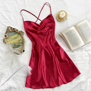 Elegant deep red satin slip dress with cross-back straps on a textured white bedsheet