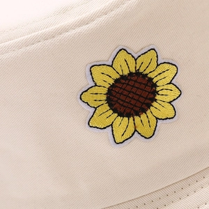 Dettaglio del ricamo a girasole su cappello alla pescatora in tela beige resistente