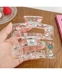 Detail of a clear acrylic hair claw clip featuring festive Santa and snowman patterns