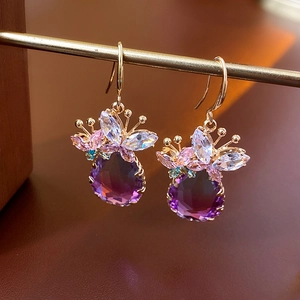 Détail macro de boucles d'oreilles papillon dorées avec zircons violets dégradés