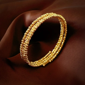 Détail d'un bracelet enveloppant multicouche plaqué or sur fond de soie marron