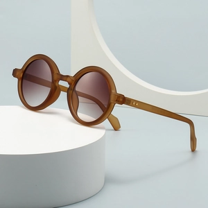 Retro amber round sunglasses with gradient lenses displayed on a white geometric stand