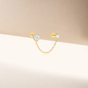 Detailed macro view of S925 sterling silver heart stud with delicate gold connecting chain