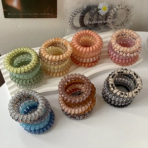 Colorful spiral phone cord hair ties in jelly colors displayed on a white wave stand
