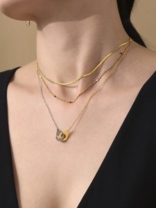 Détail d'un ensemble de colliers superposés dorés avec chaîne serpent et pendentifs