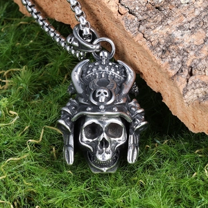 Detail of silver skull warrior pendant with metal chain on natural wood and grass background