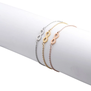 Armbanden met oneindigheidssymbool in zilver, goud en roosgoud op een witte standaard