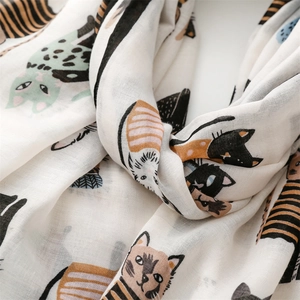 Close-up of white scarf with colorful cartoon cat prints showing soft fabric texture