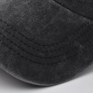 Close-up of stitched brim and washed cotton texture on a dark grey baseball cap