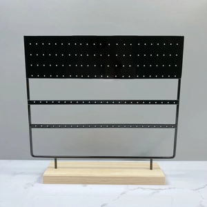 Close-up of a black multi-hole metal earring organizer with a natural wooden base