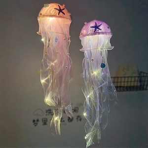 Close-up of pink and purple jellyfish hanging lamps with lace, pearls, and sea star decor
