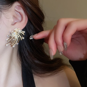 Close-up of elegant firework star earrings with pearls and crystals on a model's ear