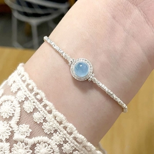 Detailed shot of an aquamarine gemstone bracelet with silver woven texture on a wrist