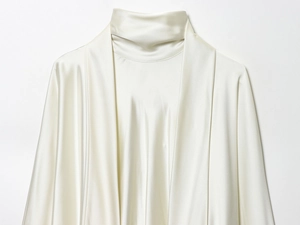 Detailed view of cream satin dress featuring a high neck and elegant draped scarf detail