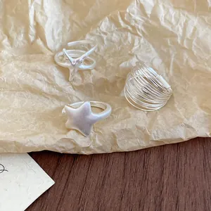 Detailed view of layered silver star rings featuring open cross and wire wrap designs