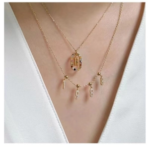 Detail view of gold S925 silver necklaces with letter H and 198 number charms