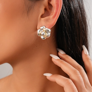 Close-up of model wearing two-tone metallic flower earrings in silver and gold finish