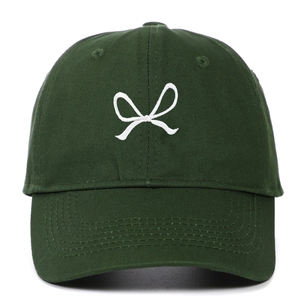 Detail of white ribbon embroidery on dark green cotton twill baseball cap fabric